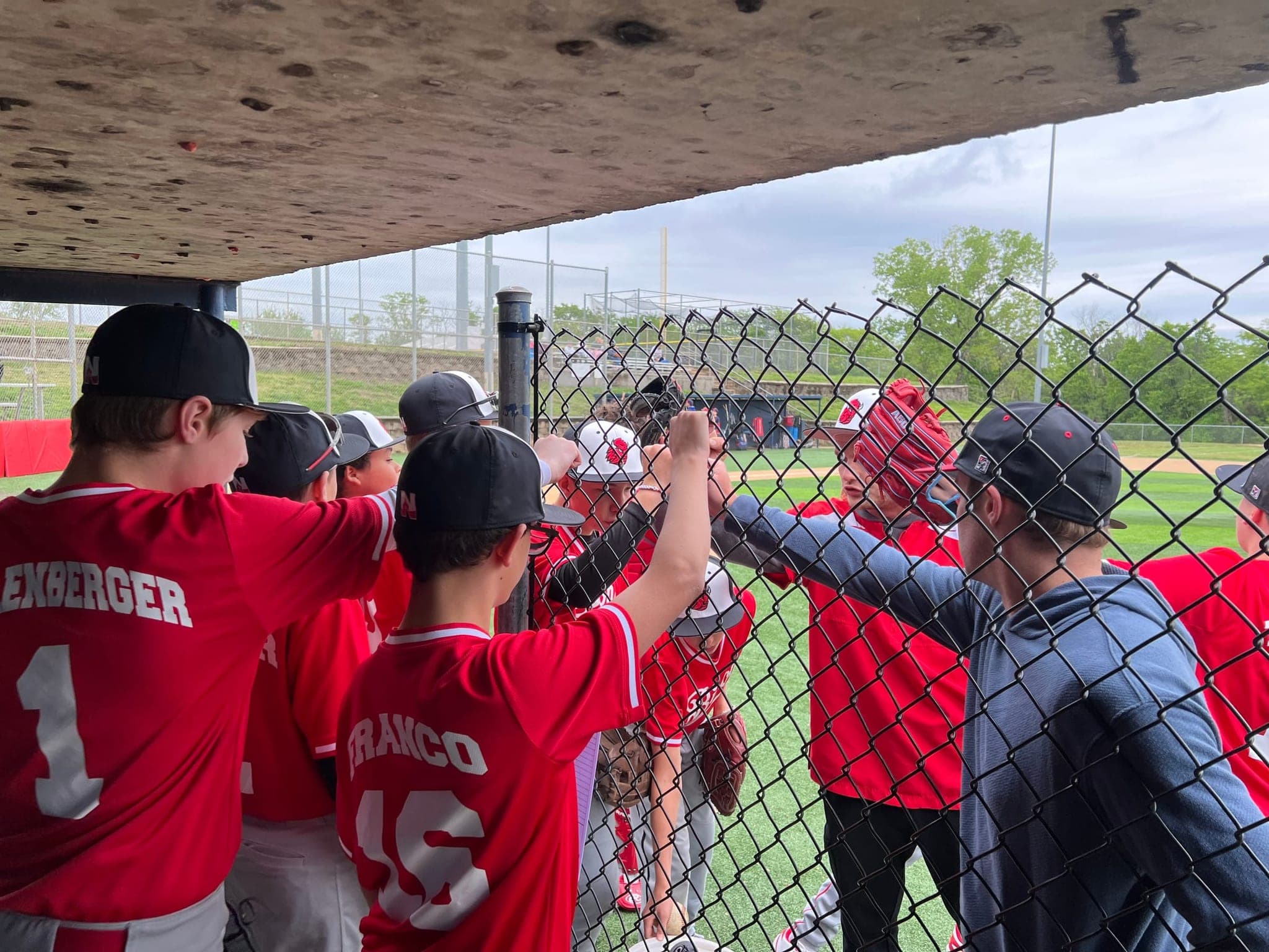A youth baseball team sharing a fist bump in the dugout